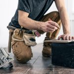 Building contractor worker using hand held worm drive circular saw to cut boards on a new home constructiion project.